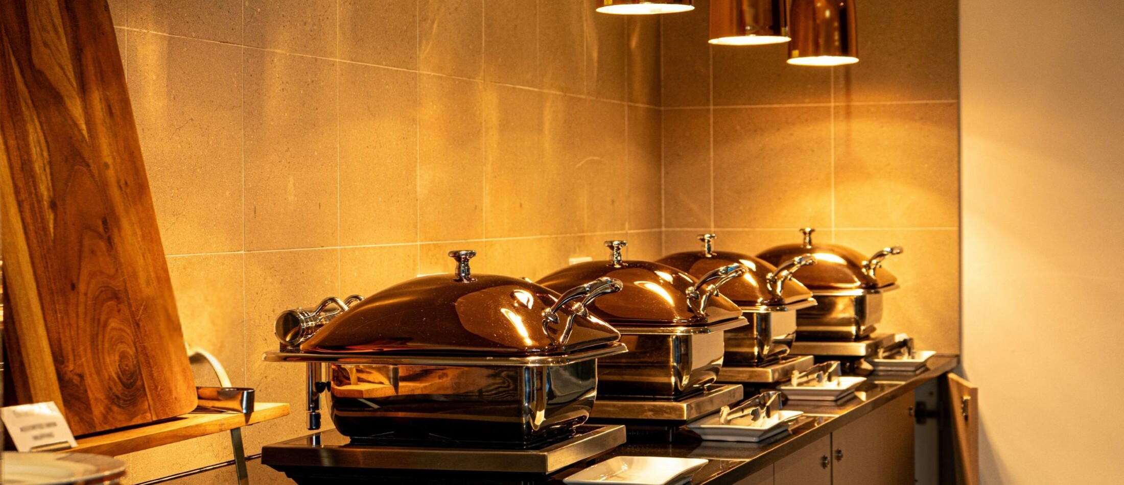 Buffet counter with multiple chafing dishes arranged under warm lighting at Comfort Resort Leura Gardens.