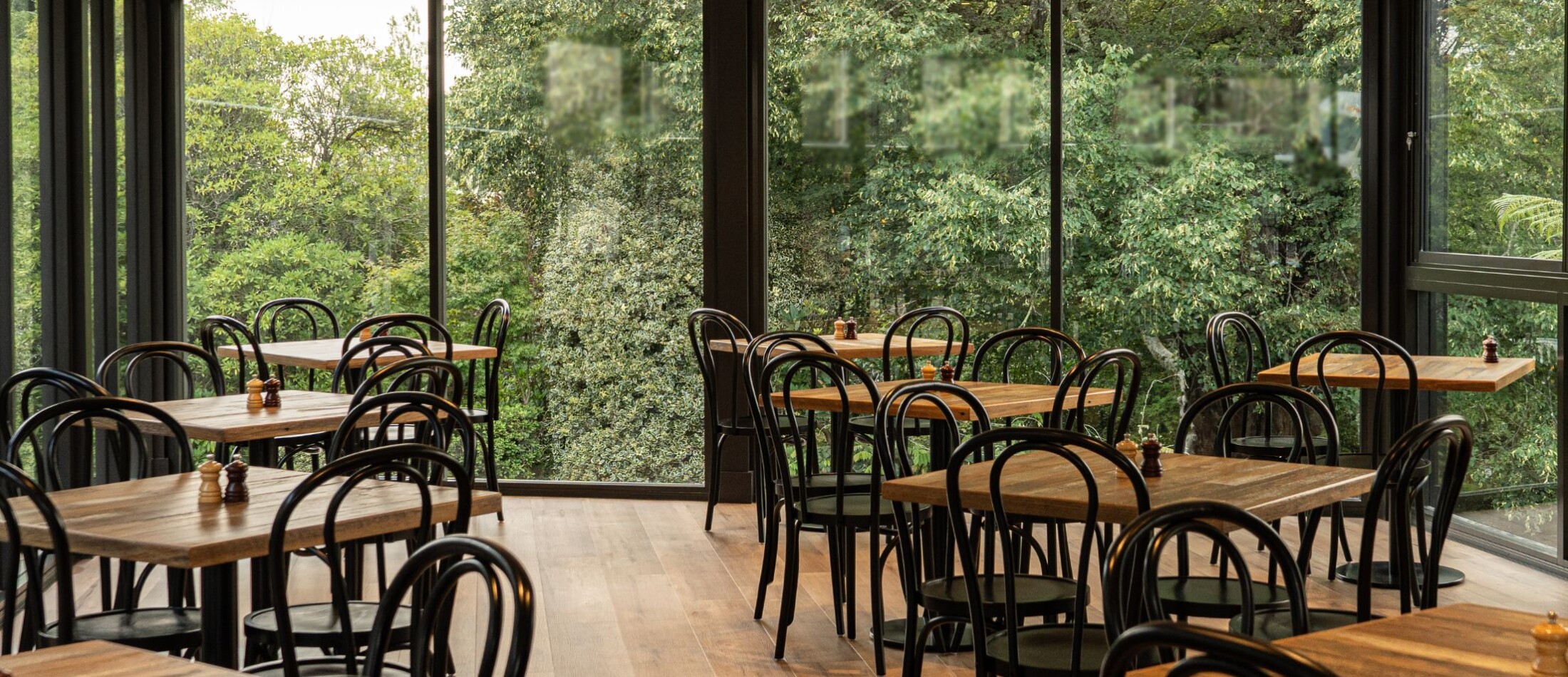 Fairways Restaurant & Bar at Comfort Resort Leura Gardens with tables and chairs positioned beside large windows overlooking greenery.